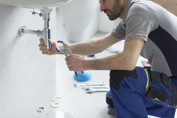 Professional plumber checking a sink drain
