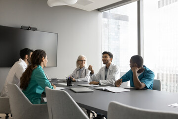 Indian male therapist wear white coat makes speech at group meeting medical seminar in modern...