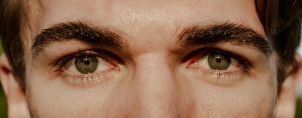 Close up of two annoyed red blood eyes of male affected by conjunctivitis or after flu, cold or...