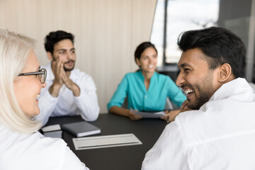 Group of doctors engaged in discussion, focus on two therapists laugh, look at each other enjoy...