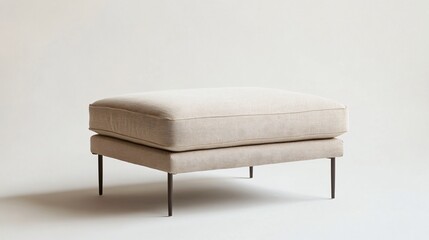 A stylish modern ottoman with a rectangular design, upholstered in soft, beige fabric, and featuring thin metal legs, centered on a neutral background