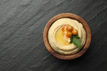 Delicious hummus with olive oil, chickpeas and parsley in bowl on grey textured table, top view. Space for text