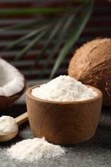 Organic coconut flour in bowl, spoon and fresh fruits on grey table