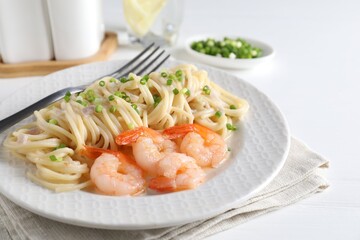 Delicious pasta with shrimps and green onions on white table, closeup