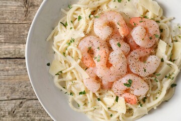 Delicious pasta with shrimps and cheese on wooden table, top view