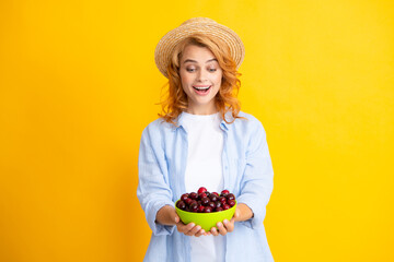 Young woman eats sweet cherries. Portrait of a beautiful girl with cherry on yellow background. Summer fruit picking season. Natural vitamins.