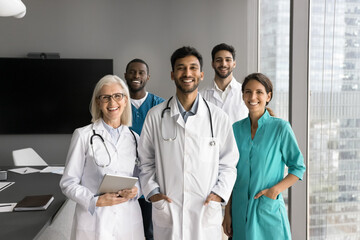 Portrait of five young and mature multiethnic medical professionals, therapists or GP wear uniforms...