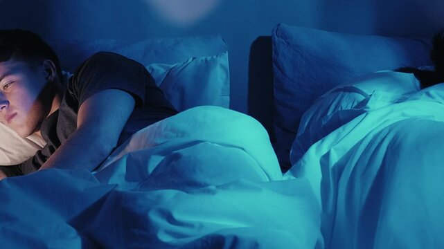 Gadget couple. Digital night. Social media addiction. Unhappy husband wife phubbing in bed using devices late in dark blue light.