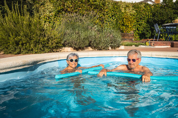 Cute Senior couple Enjoying Water Workout with Foam Noodles