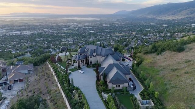 road leads to a mansion on a green hill in mountainous city at sunset time in Bountiful, Utah