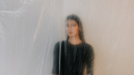 Woman aesthetic with soft blurred effect behind translucent plastic sheet showcasing artistic...