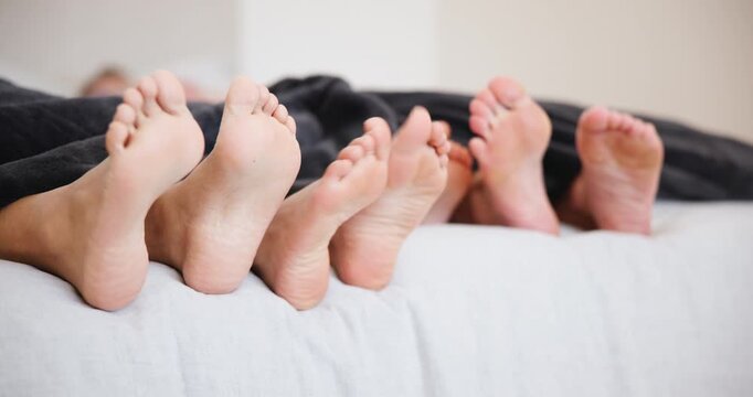 Bed, sleeping and feet of family wake up in the morning after nap, relax or rest in their home together. Toes, love and barefoot people in bedroom with movement, bond or weekend, vacation or freedom