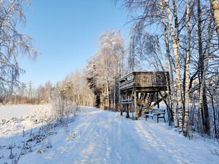 Wooden birdwatching tower against the backdrop of snowy trees and the lake in winter, hobby in Finland, Suomenoja