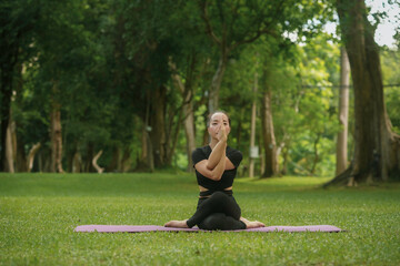 Young woman is practicing yoga in a lush green park, finding peace and connecting with nature