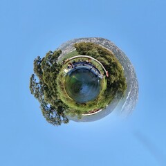 Little planet transformation of spherical panorama 360 degrees. Spherical abstract aerial view in field with trees. Curvature of space.