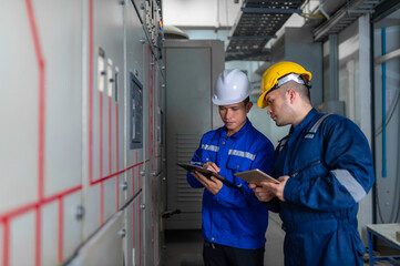 Electrical engineers and technicians work together to solve electrical system failures in industrial control rooms.supervisor maintains the circuit cabinet.