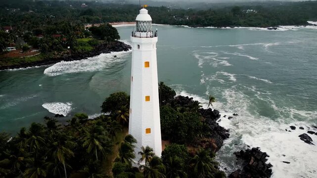 Reveal shot of Point Dondra Lighthouse in Sri Lanka, highlighting the stunning transition from coastal landscape to the iconic structure
