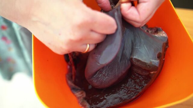 woman's hands delicately peel away the packaging from beef liver, signifying the beginning of a culinary journey. The texture and freshness evoke anticipation for a delicious dish