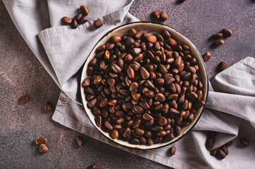 Close up of ripe pine nuts in the shells on a plate on the table top view