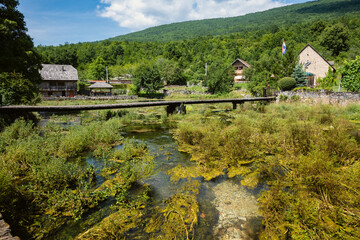 Fototapeta premium Wonderful Majerovo Vrilo, old mill houses and bridges made from wood and stone in the village of Sinac, Croatia, built around Gacka river source