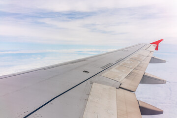 Fototapeta premium View from the airplane window at a beautiful cloudy sky and the airplane wing