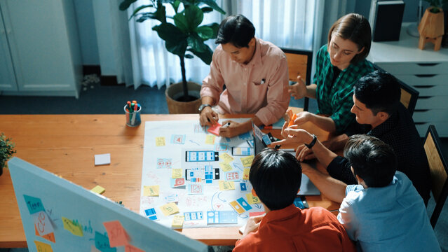 Top view of diverse business people brainstorming idea by using mind map. Creative marketing team looking at data analysis from laptop screen while manager choose idea and show to team. Convocation.