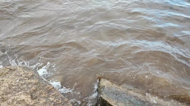 waves crash against rocks on the river bank