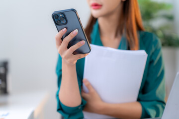 Voice Notes for Productivity:  A businesswoman streamlines her workflow, dictating notes into her smartphone while reviewing documents at her desk.