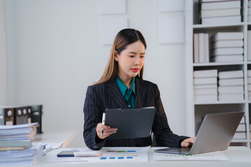 Focused Professional: A dedicated businesswoman meticulously analyzes data on her laptop,...
