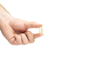 Male hand holding omega 3 soft gel capsule isolated on white background