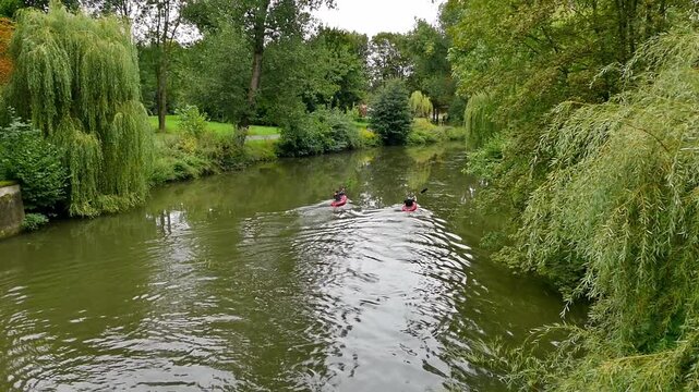Two kayaks floating down the river in the park.