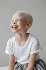 A young albino girl wearing an oversize white t-shirt, grey background