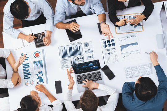 Top view analyst team utilizing BI Fintech to analyze financial data at table in meeting room. Analytic BI dashboard power on paper for business insight and strategic marketing planning. Prudent