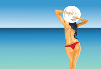 A beautiful fashion woman in a stylish bikini and sun hat enjoys a tropical summer vacation on the sandy beach by the blue ocean water under a clear sky