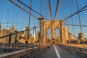 Brooklyn Bridge over East River viewed from New York City Lower Manhattan waterfront at sunrise