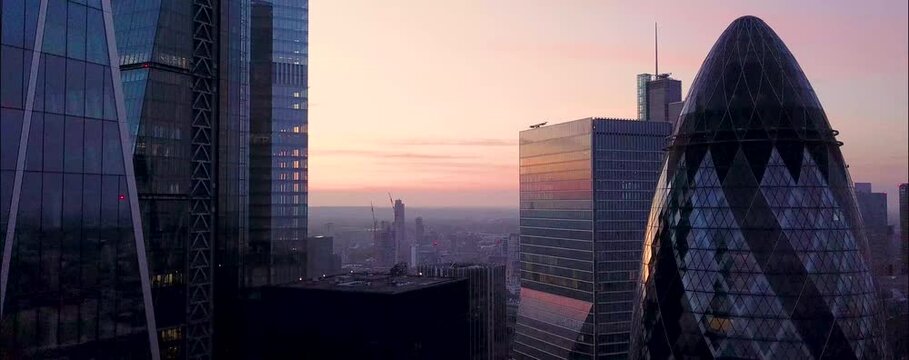 
As the sun begins to set over London, the city's iconic skyline is bathed in a warm, golden glow. From a drone's aerial perspective, the skyscrapers rise majestically, their glass facades reflecting 