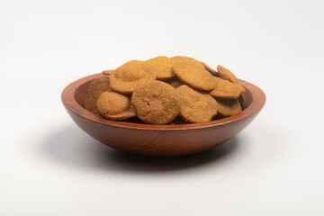 Studio shot of Indian Gujarati tea time snack Bajri Vada in a carved wooden bowl, isolated on white