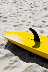Obraz premium Yellow surfboard lying on beach sand