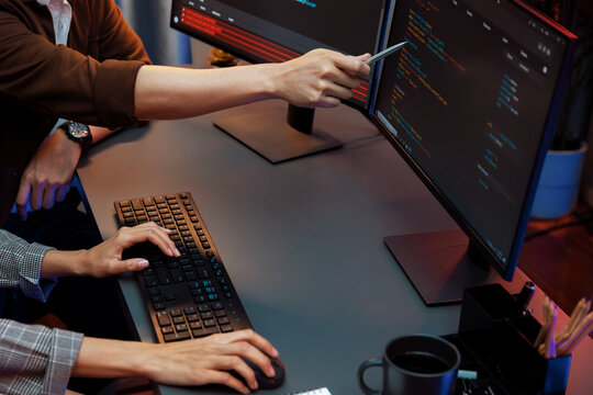 IT developers discussing with point to intelligent website development coder system running data online two screens information technology at neon light room at modern office. Infobahn.