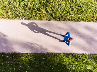 Aerial view of a runner running through the park on a jogging path. Morning running training.
