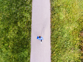 Fototapeta premium Aerial view of a runner running through the park on a jogging path. Morning running training.