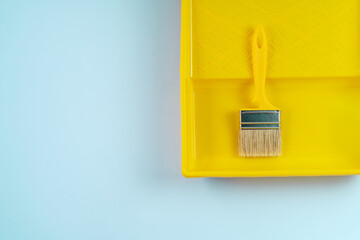Yellow building brush for walls painting on a plastic tray, individual housing construction concept