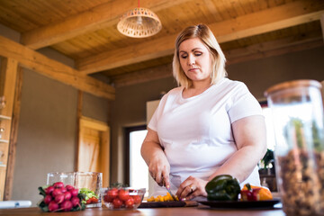 Overweight woman in the kitchen, making homemade lunch. Choosing healthy food, making and eating...