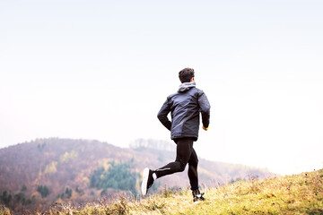 Male runner jogging in nature on dirt running trail. Morning running training for young man.