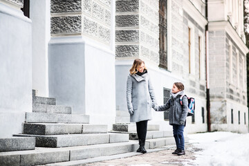Mother taking daughter to school, saying goodbye in front of the school building, heading to work....