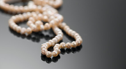 Pearl necklace over black background, close up. Beautiful Natural pearls beads, elegant accessories. Border design 