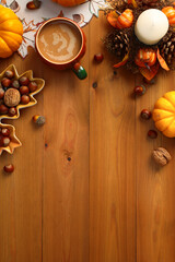 Autumn flat lay composition with coffee cup, pumpkins, decorative candle with pine cones, leaf-shaped plate with nuts, acorns on wooden table.