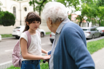 Fototapeta premium Grandmother explaining to granddaughter how to ride a scooter safely before leaving for school.