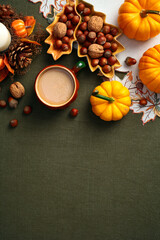 Thanksgiving or Autumn background with pumpkins, nuts, candle, leaves, coffee cup on green cloth. Flat lay, top view, vertical.