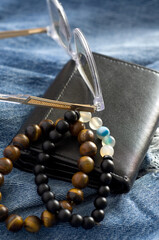 Macro Still Life of Leather Wallet, Reading Glasses and Men Bracelets on Old Denim Jeans